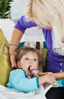 Sick little girl getting syrup from her caring mother 