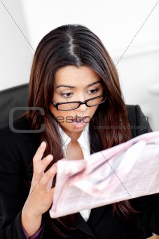 Shocked businesswoman reading a newspaper 
