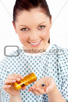 Smiling caucasian female patient holding pills