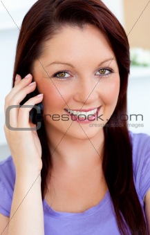 Delighted young woman using her cellphone on a sofa