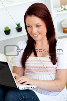 Beautiful caucasian woman using her laptop lying on the sofa in 
