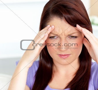 Dejected woman having a headache sitting in the living-room