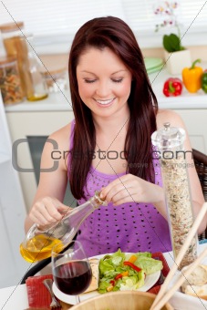 Bright woman eating a salad with oil in the kitchen