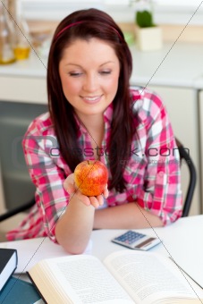 young woman looking at an apple in the kitchen