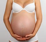 Young pregnant woman in white underwear holding her belly