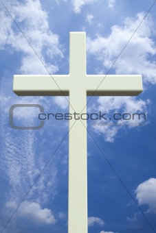 White Christian cross in front of a cloudy sky