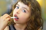 brunette little girl eating playing plastic spoon