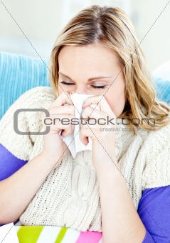 Diseased woman lying on a sofa with tissues and blowing
