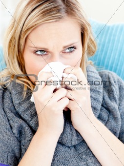Dejected woman lying on a sofa with tissues and blowing