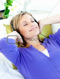Relaxed caucasian woman listening to music with headphones lying