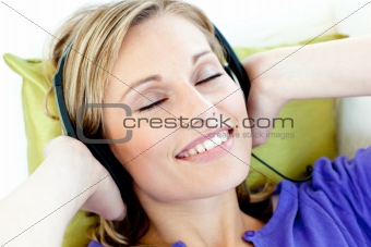 Charming caucasian woman listening to music with headphones lyin