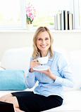 Smiling businesswoman drinking coffee sitting on a sofa