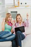 Enthusiastic women looking at a laptop sitting on the sofa celeb