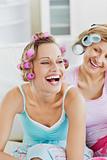 Laughing women wearing hair rollers sitting on the sofa