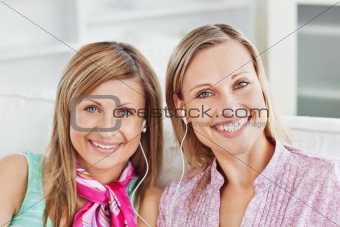 Captivating two female friends listen to music smiling at the ca
