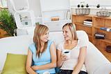 Cheerful two women drinking coffee and talking while sitting on 