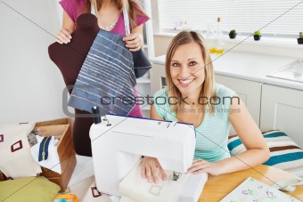 Smiling woman sewing in the kitchen with her friend