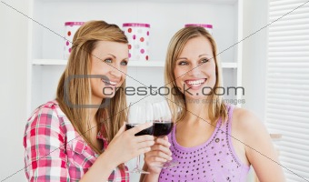 Animated female friends drinking wine in the kitchen