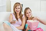 Relaxed female friends eating popcorn watching tv 