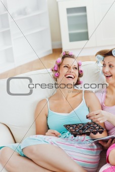 Laughing friends eating chocolate at home