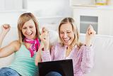 Enthusiastic friends with arms up looking at the laptop 
