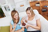 Delighted female friends eating a chocolate cake at home