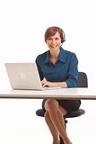 Young business woman sitting at desk with computer and headset