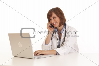Portrait of young woman doctor in white coat at computer using phone
