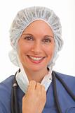 Portrait of smiling young woman doctor in scrubs pulling on mask