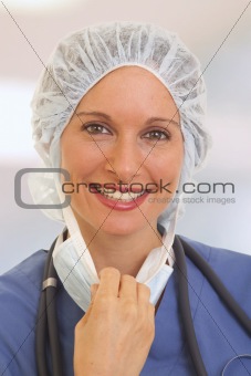 Portrait of smiling young woman doctor in scrubs pulling on mask