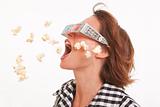 Side view portrait of young woman with 3D glasses and popcorn in the air