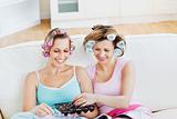Positive female friends with hair rollers eating chocolate readi