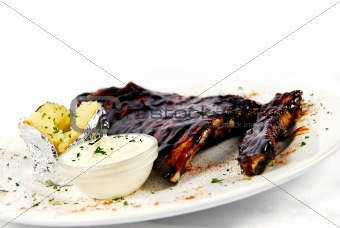Pork ribs with a baked potato and sour cream