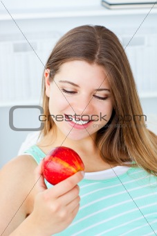 cute woman looking at an apple sitting in the living-room