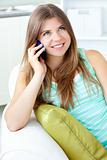 Positive woman talking on phone sitting on a sofa