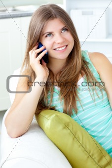 Positive woman talking on phone sitting on a sofa