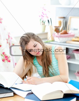 Bored caucasian student doing homework sitting in the kitchen
