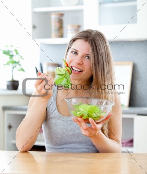 charming woman  enjoying a healthy salad sitting at the table