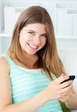 Smiling young woman texting on her cellphone in the living-room