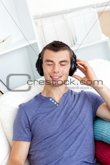 Relaxed young man listening to music sitting on the couch in the