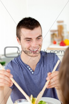 Happy man putting salad on a plate having dinner with his girlfr