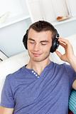 Handsome young man listening to music with headphones in the liv