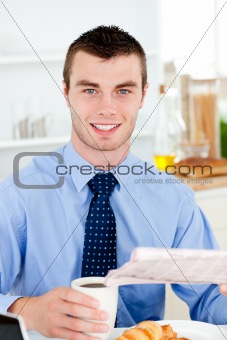 Happy businessman reading the newspaper drinking coffee in the m