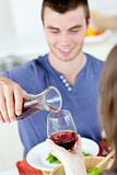 Cute man dining with his girlfriend at home serving her wine