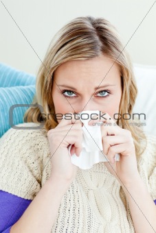 Morbid woman using a tissue sitting on a sofa at home