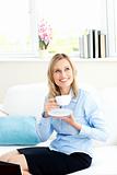 Smiling businesswoman holding a cup of coffee sitting on a sofa