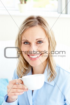 Captivating businesswoman holding a cup sitting on a sofa