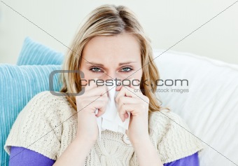 Diseased woman using a tissue sitting on a sofa