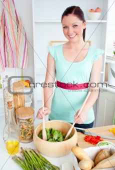 Concentrated young woman preparing a salad in the kitchen