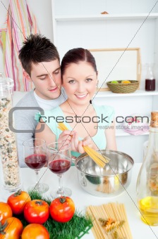 Young couple preparing spaghetti in the kitchen and drinkng wine